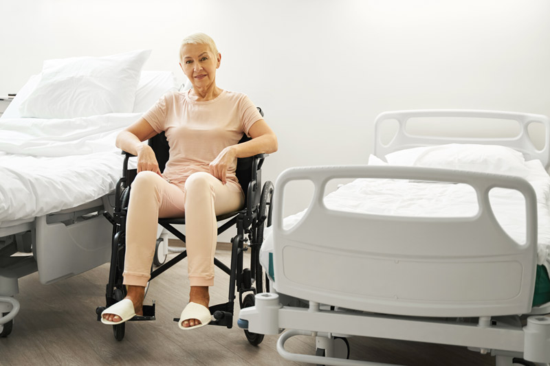 ¿Cómo elegir una cama articulada? Mujer en silla de ruedas entre dos camas hospitalarias