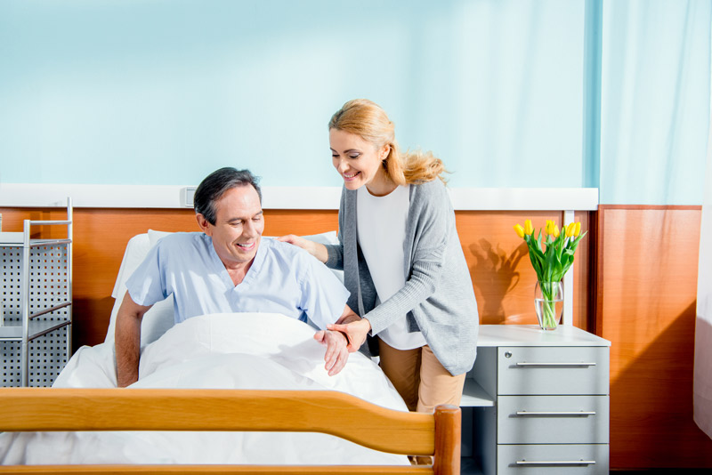 ¿Cómo elegir una cama articulada? Persona ayudando a incorporarse a paciente en cama articulada con patas