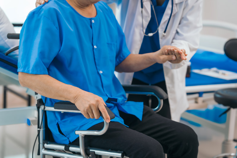 Cómo elegir una silla de ruedas Persona mayor recibiendo asistencia médica para sentarse en una silla de ruedas