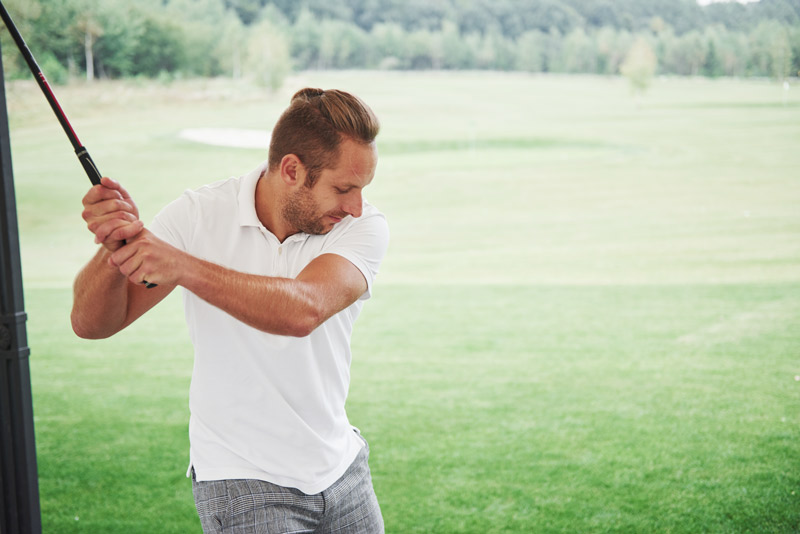 Codo de golfista: causas, síntomas y tratamiento eficaz Jugador de golf profesional apuntando un golpe, ejemplo de deporte que puede causar codo de golfista