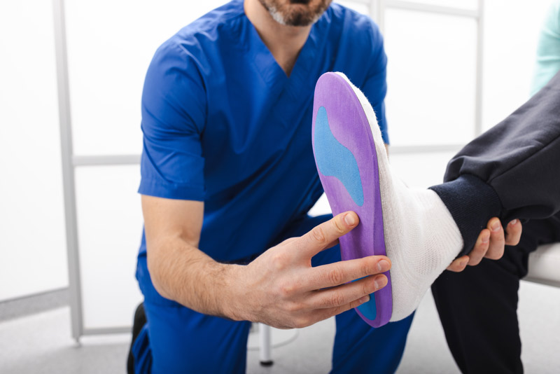 Fascitis plantar: qué es, síntomas, tratamiento y mejores productos para aliviarla Especialista colocando una plantilla ortopédica para tratar la fascitis plantar