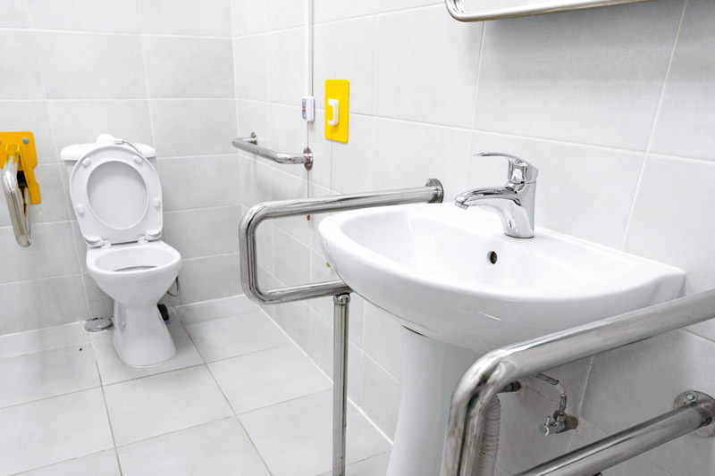 Cómo ayudar a una persona mayor a ir al baño de forma segura Imagen de baño adaptado para personas mayores con barras de apoyo y lavabo accesible