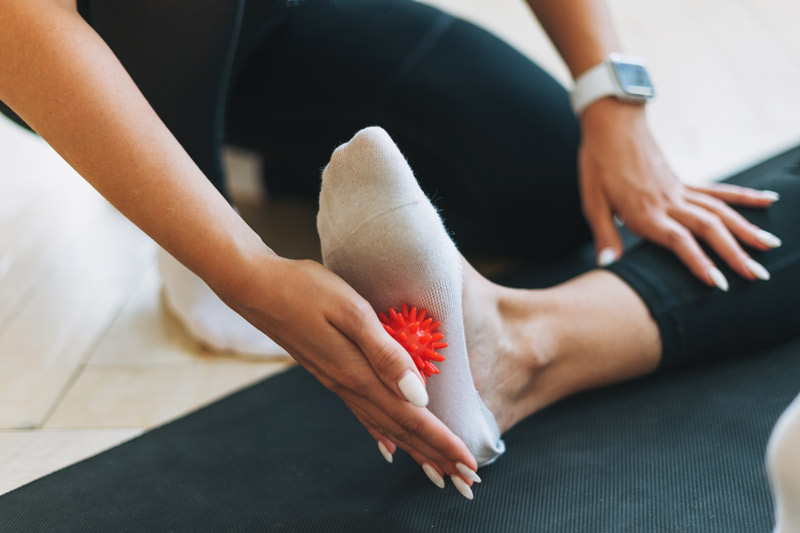 Fascitis plantar: qué es, síntomas, tratamiento y mejores productos para aliviarla Persona masajeando la planta del pie con pelota para aliviar fascitis plantar