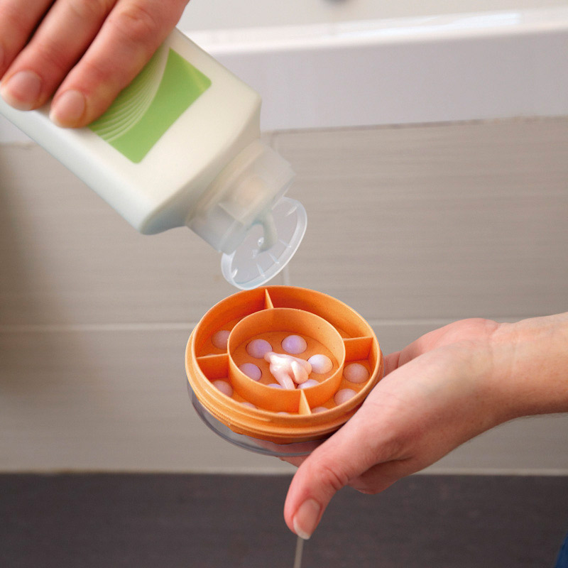 Aplicador de crema Mano rellenando el cabezal de un aplicador de crema con loción