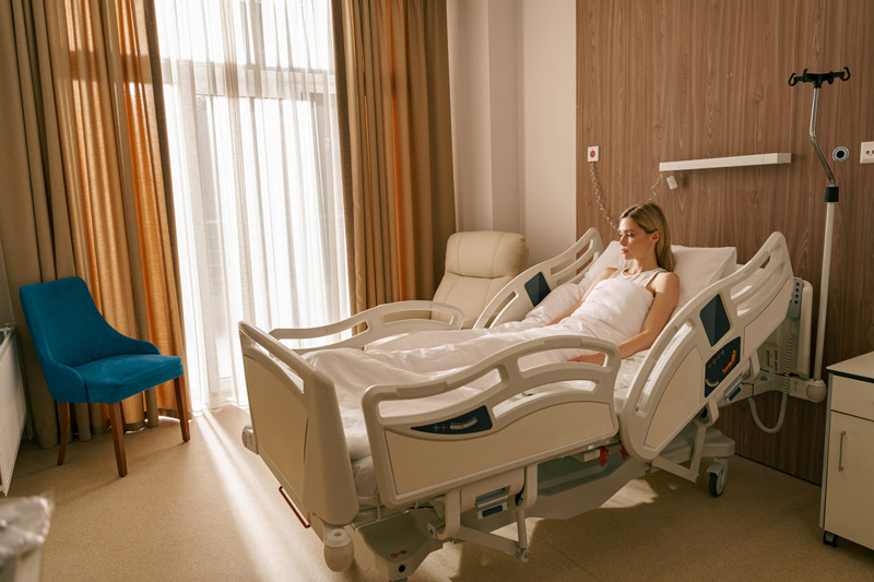 ¿Qué es una cama hospitalaria? Mujer recostada en cama hospitalaria articulada con funciones eléctricas