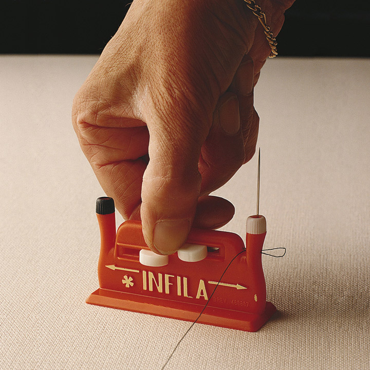 Enhebrador de agujas de coser Mano utilizando el enhebrador de agujas INFILA sobre una mesa