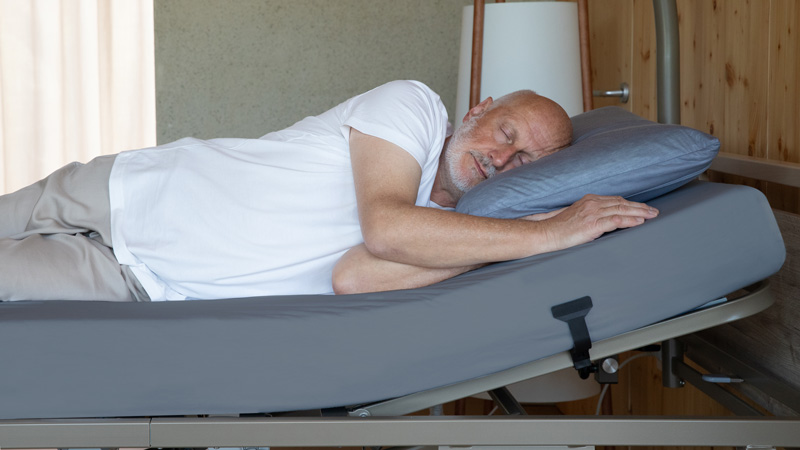 Sábana bajera Select BDermofresh Persona descansando sobre sábana bajera gris colocada en colchón de cama articulada