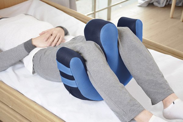 Cojín volteador para encamados Paciente en cama con las piernas apoyadas en el cojín volteador para facilitar la rotación